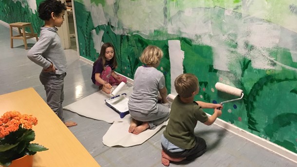 Børn fra øen er i færd med at male Fejøs Børne- og Kulturhus, som har erstattet øens gamle skole og i dag rummer skole til og med 4. klasse.