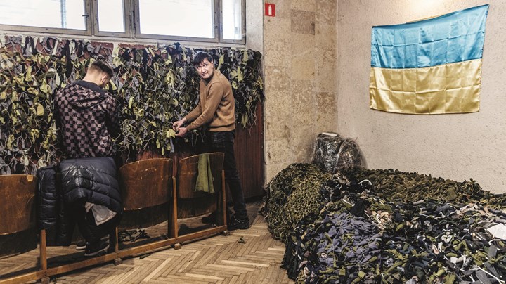 Til højre står Oleg Pliner og hjælper til med fremstillingen af camouflagenet i en festsal på kollegium tilknyttet Lviv Polytekniske Universitet. Han er flygtning fra Mariupol og har netop sagt farvel til sin datter og kone.